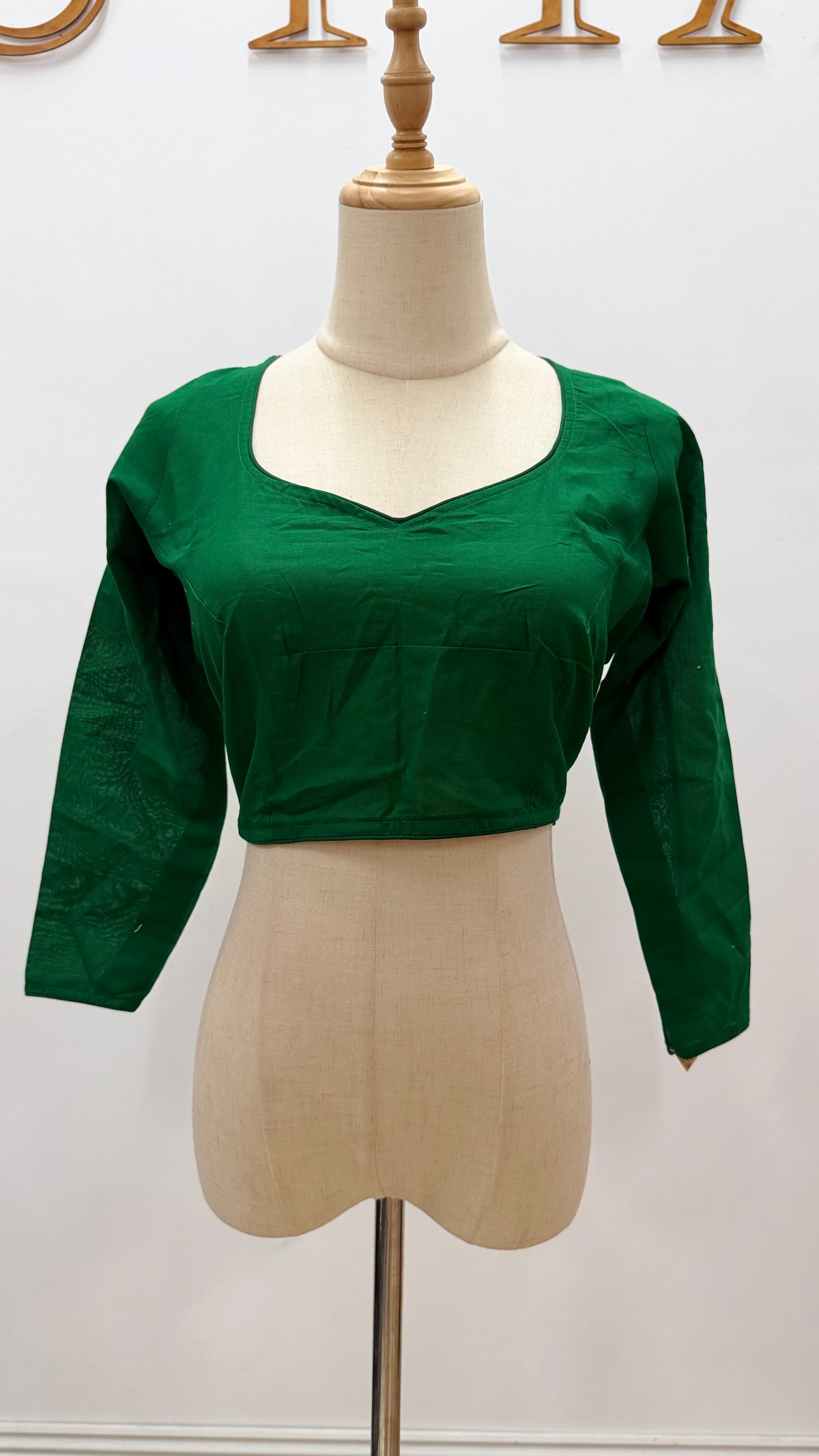 Green blouse on a mannequin against a white background