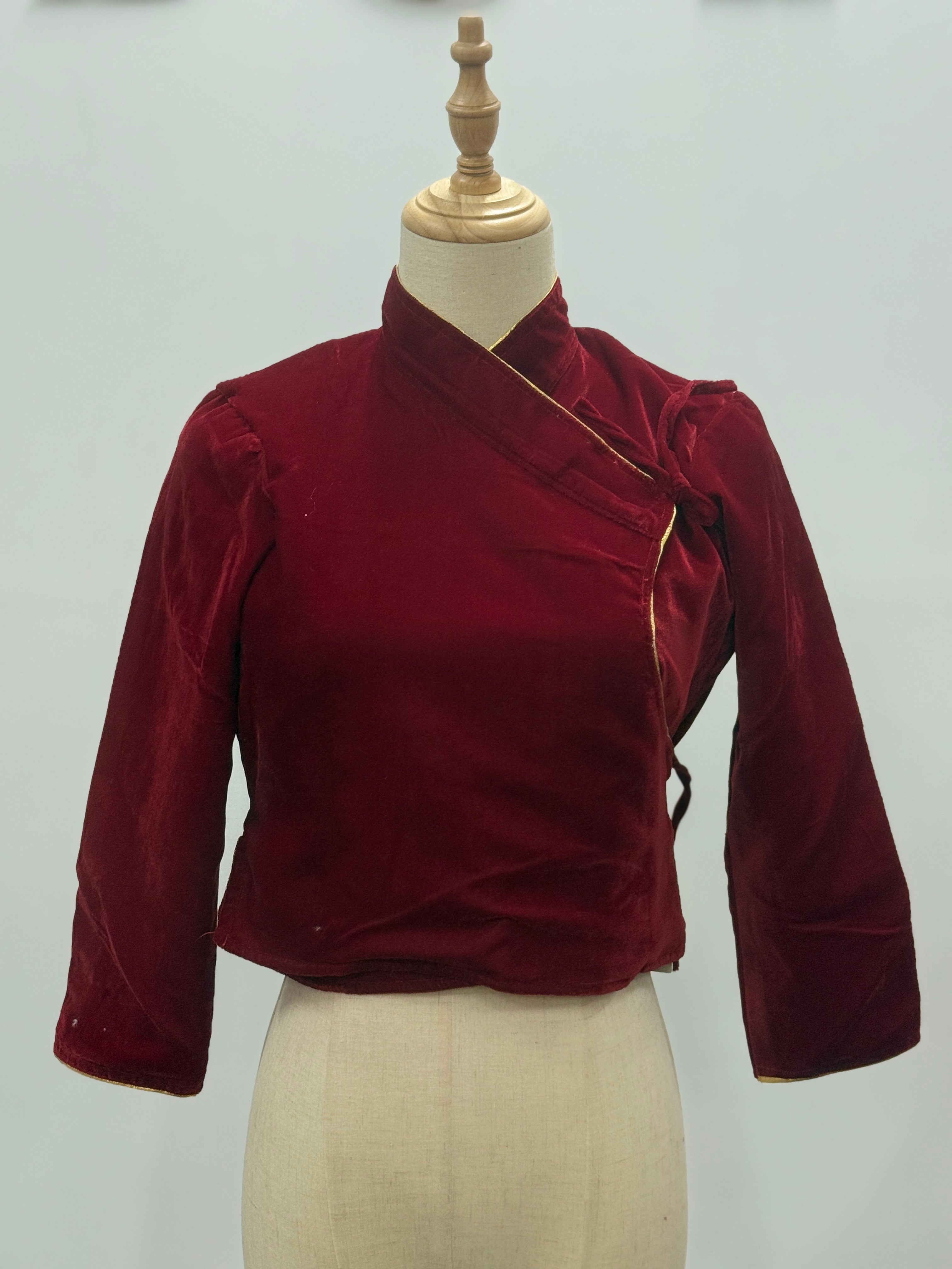Red velvet top on a mannequin against a plain background