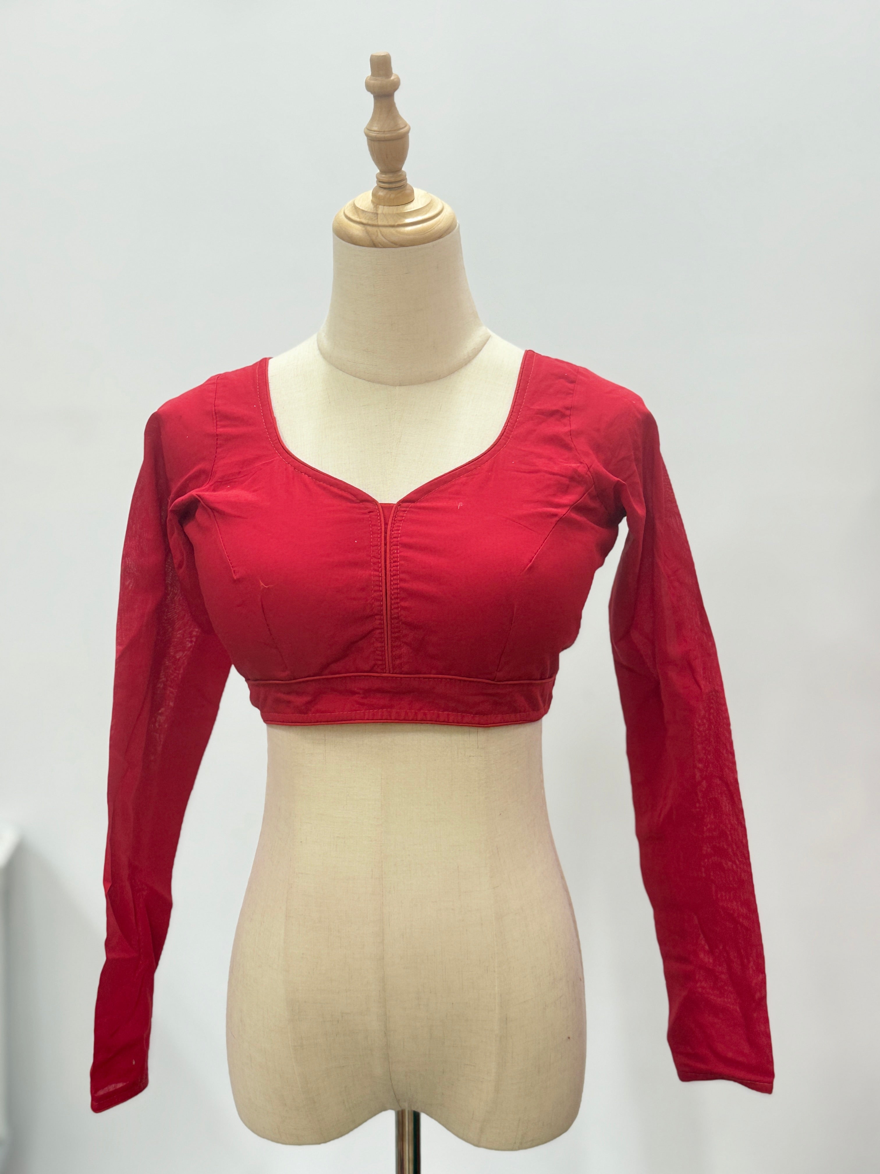 Red long-sleeve crop top on a mannequin against a plain background
